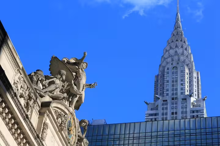 Grand Central Terminal sculptures with Chrysler Building spire against blue sky in Midtown Manhattan