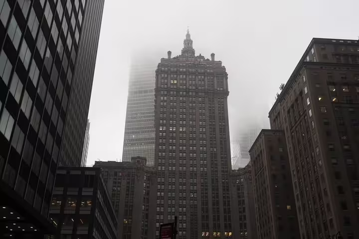 Foggy Midtown NYC skyscrapers and historic buildings viewed from street level on overcast day