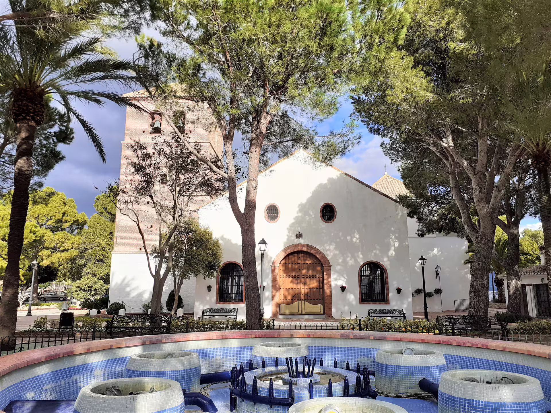 Mijas group walking tour view of Parque de la Muralla with fountain and the white church in historic Mijas Pueblo