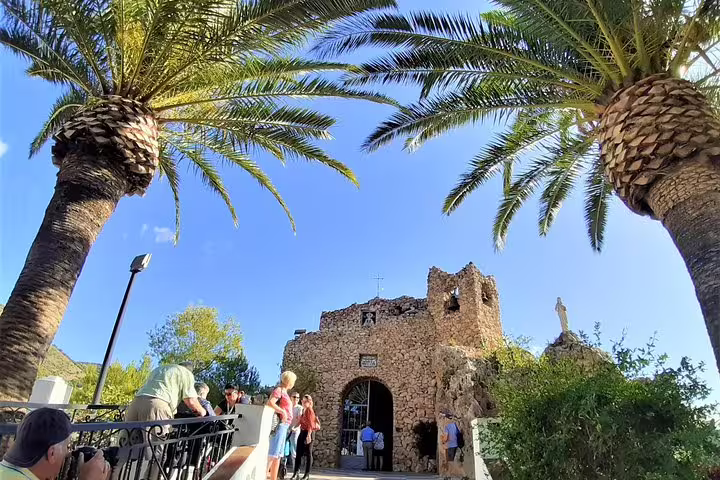 Palm-framed view of Mijas Pueblo historic chapel ruins on a private excursion from Costa del Sol