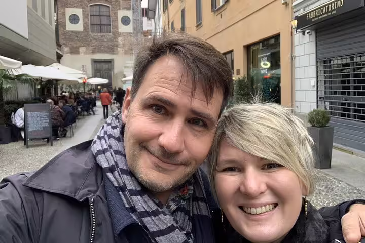 Couple smiling on a cobblestone street in Milan's Brera district with outdoor cafes in background