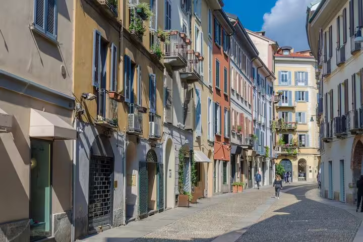 Colorful historic buildings lining a cobblestone street in Milan's Brera neighbourhood on a sunny day