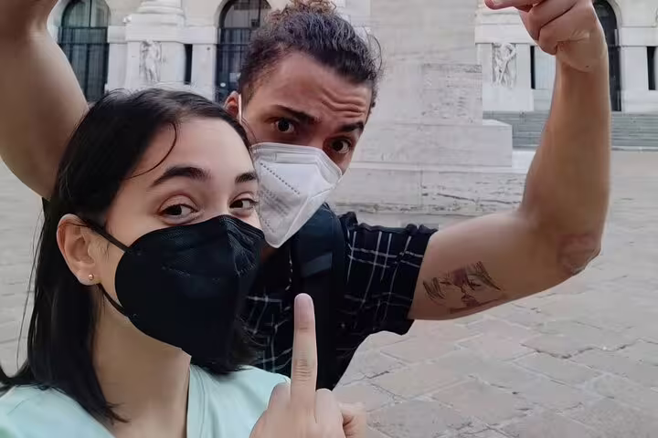 Two tourists wearing face masks taking a selfie during a self-guided walking tour in Milan city center