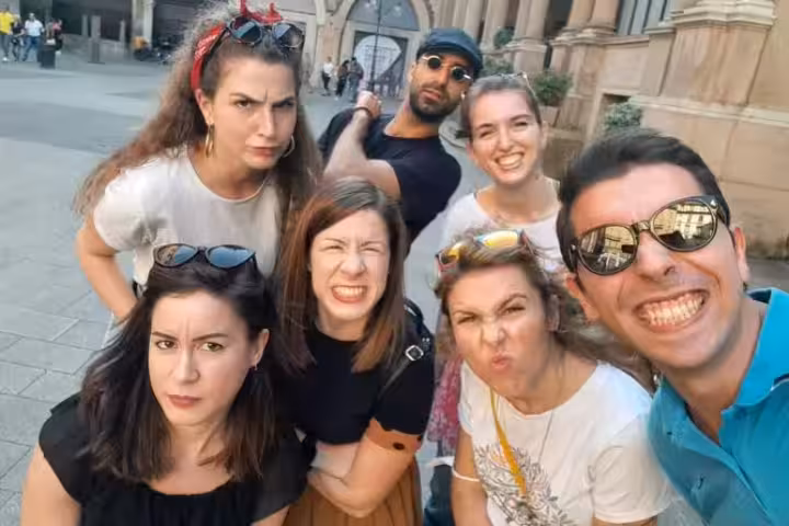 Group of seven friends making fun faces during a self-guided walking tour in Milan city center
