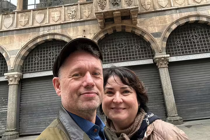 Couple taking selfie in front of historic Banca Popolare di Lodi building in Milan