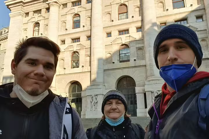 Three tourists posing in selfie in front of historic Milan building during self-guided city walking tour