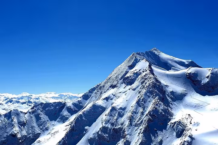 Majestic snow-capped Alpine peak under clear blue sky, showcasing scenic beauty on Milan to Courchevel route.