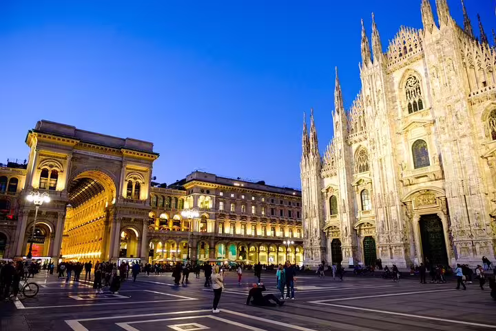 Milan Duomo Cathedral and Galleria Vittorio Emanuele II illuminated at dusk with tourists in Piazza del Duomo
