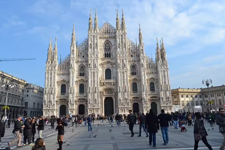 Visitors explore Milan's iconic Duomo Cathedral on a sunny day, a highlight of private sightseeing tours in the city.