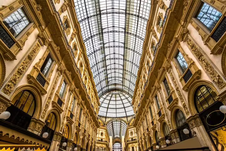 Interior of Galleria Vittorio Emanuele II in Milan with ornate arched glass ceiling and gold facades