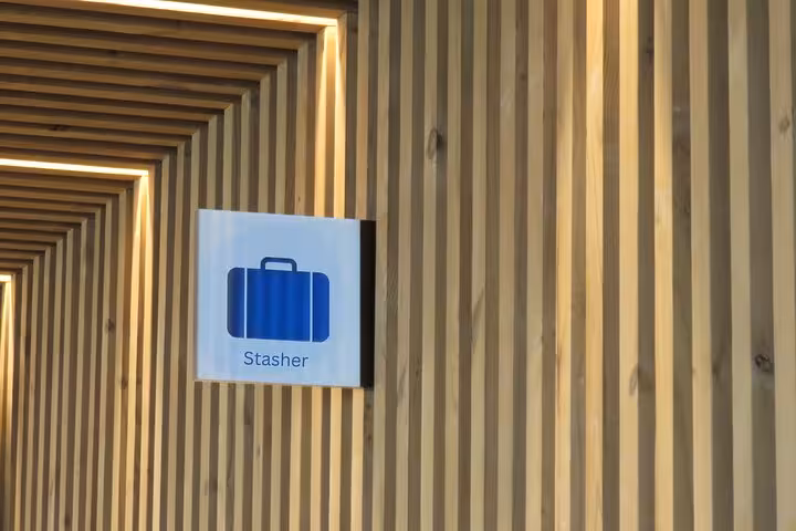 Stasher sign on wooden wall for secure luggage storage near Milan Central Station, convenient baggage drop-off