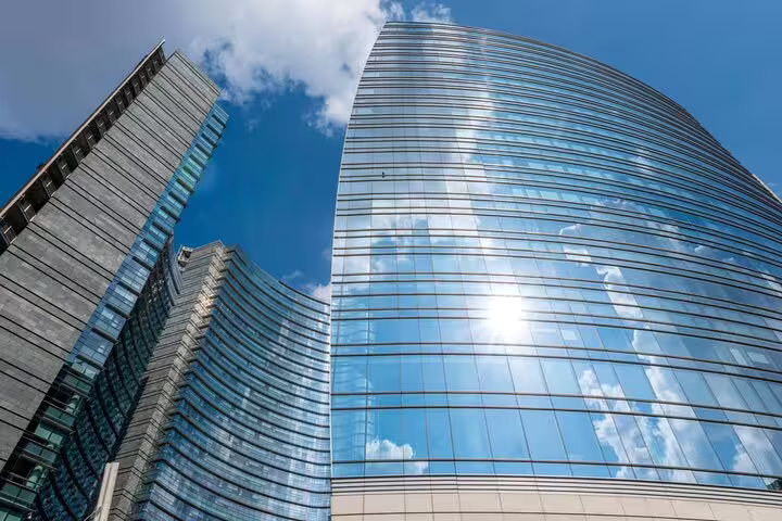 Modern glass skyscrapers reflecting blue sky and clouds in Milan's contemporary business district