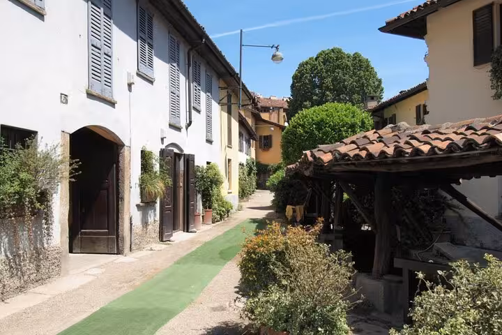 Narrow cobblestone alley with historic buildings and lush greenery in Milan's Navigli district