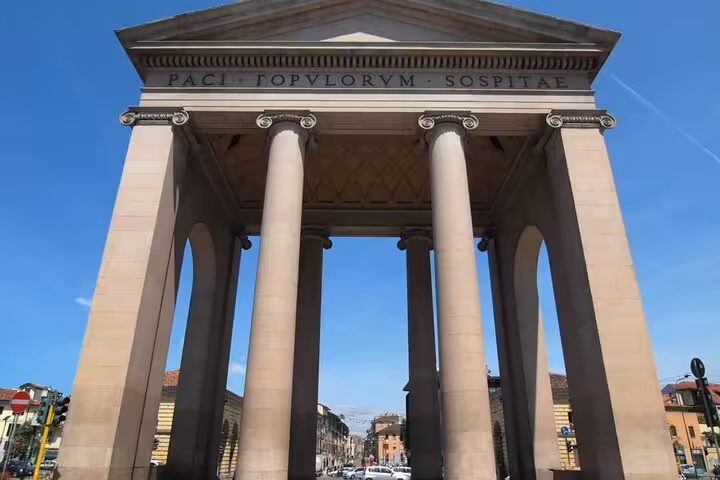 Neoclassical stone arch with Ionic columns and Latin inscription in Milan city street