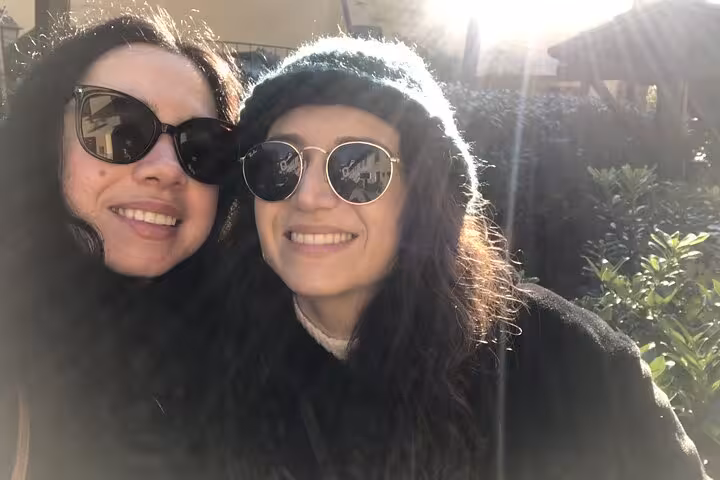 Two smiling women wearing sunglasses on a sunny outdoor walking tour in Milan