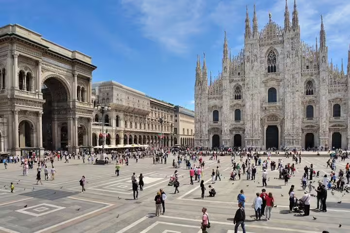 Tourists explore Piazza del Duomo in Milan on a sunny day, admiring the Duomo Cathedral and Galleria Vittorio Emanuele II