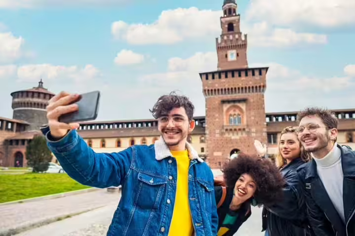 Group of happy tourists taking a selfie in front of Milan's historic Sforza Castle during a private 2-hour city tour.