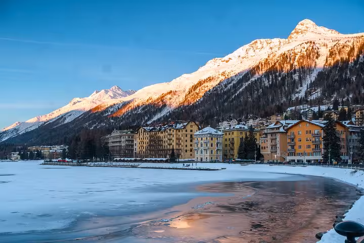 Scenic view of snow-capped mountains and frozen lake in St. Moritz, highlighting a breathtaking destination from Milan.
