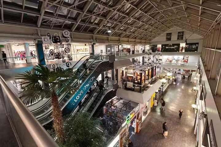 Milan train station shopping gallery with escalators, pickup point for Milan to Switzerland private day tour