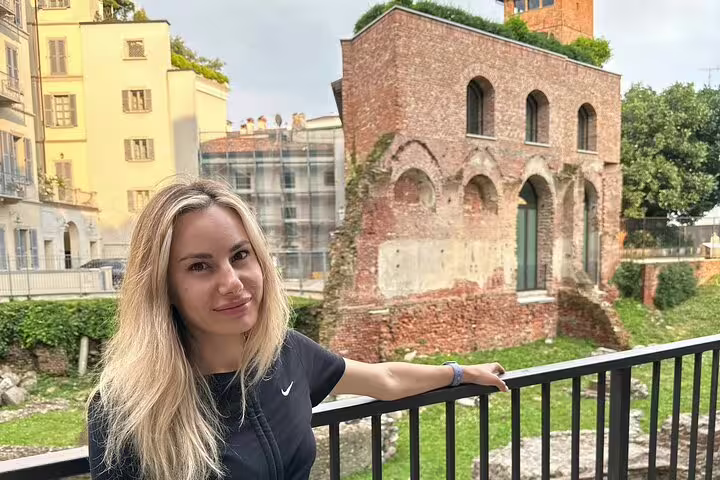 Woman posing at railing with ancient Roman brick ruins in Milan city center background