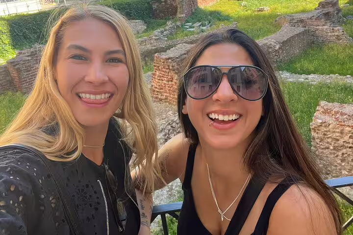 Two smiling women taking a selfie at ancient ruins during a Milan walking tour