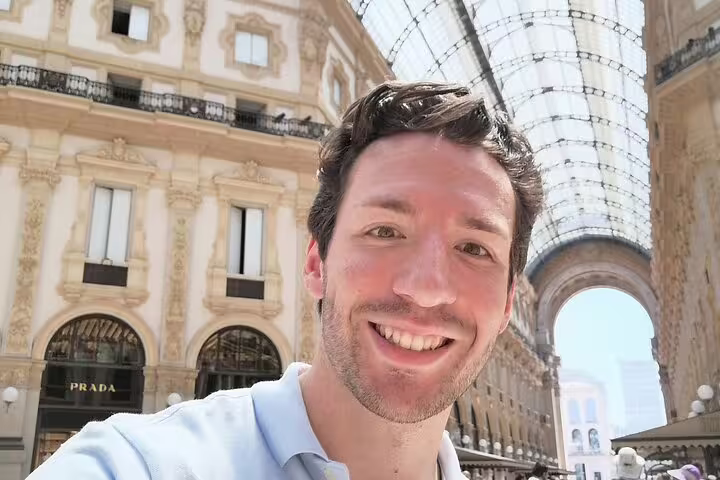Smiling man taking selfie inside Galleria Vittorio Emanuele II Milan with Prada store in background
