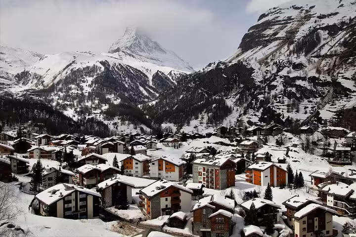 Snow-covered Zermatt village nestled in the Swiss Alps with mountain peaks in the background.