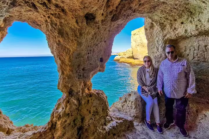 Scenic view of tourists exploring the stunning Algar Seco caves during a private Milfontes to Algarve boat tour, with turquoise waters.