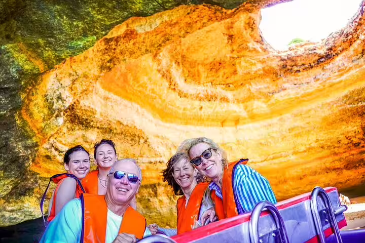 Group enjoying a vibrant boat tour inside the stunning Benagil Caves during the Milfontes to Algarve private excursion.