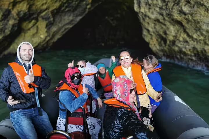 Tourists enjoy a boat trip to the Benagil caves on the Milfontes to Algarve private tour, wearing life jackets and smiling.
