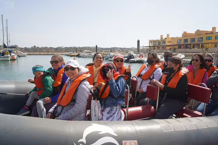 Tourists in life jackets enjoy a boat trip to Benagil caves on the Milfontes to Algarve private tour, surrounded by scenic waterfront views.