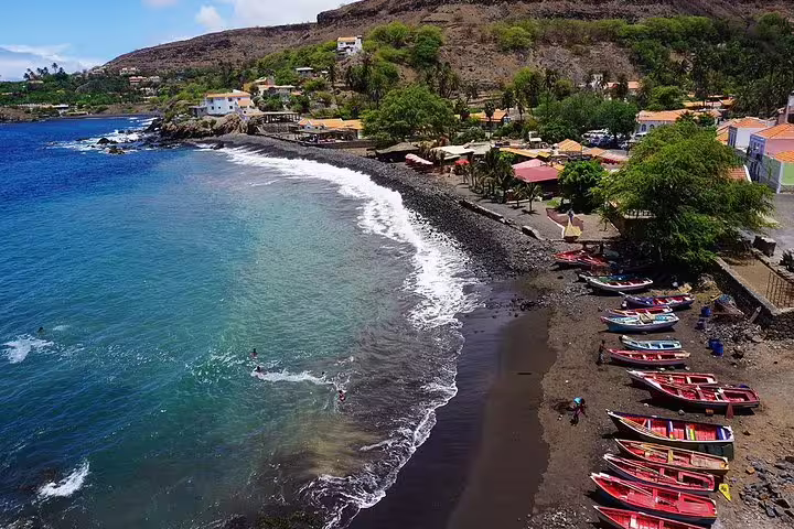 Scenic coastal view of Mindelo's shoreline with colorful fishing boats and clear blue waters in São Vicente.