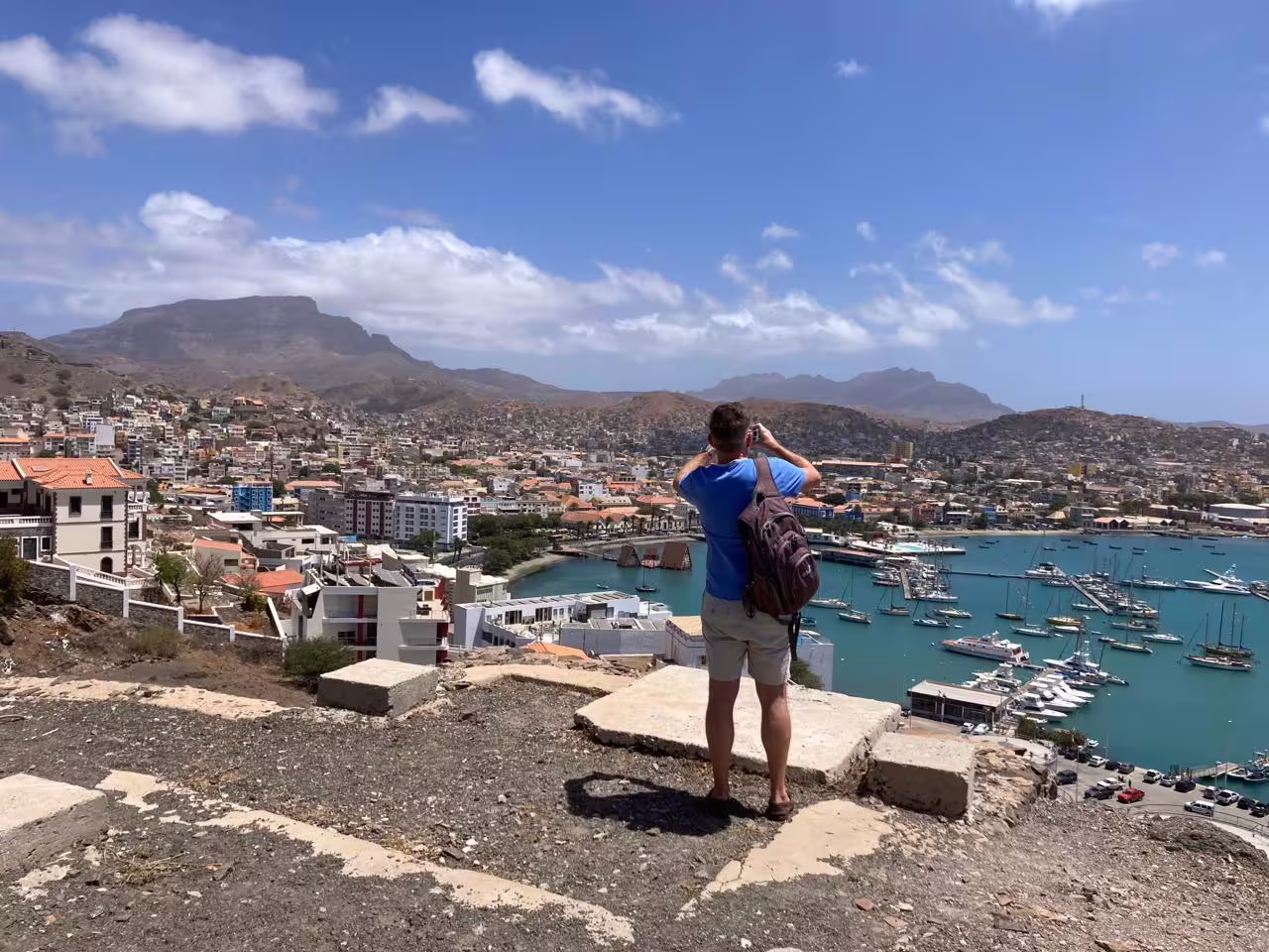 Traveler capturing panoramic view of Mindelo harbor and mountains on a full-day São Vicente island tour in Cape Verde.