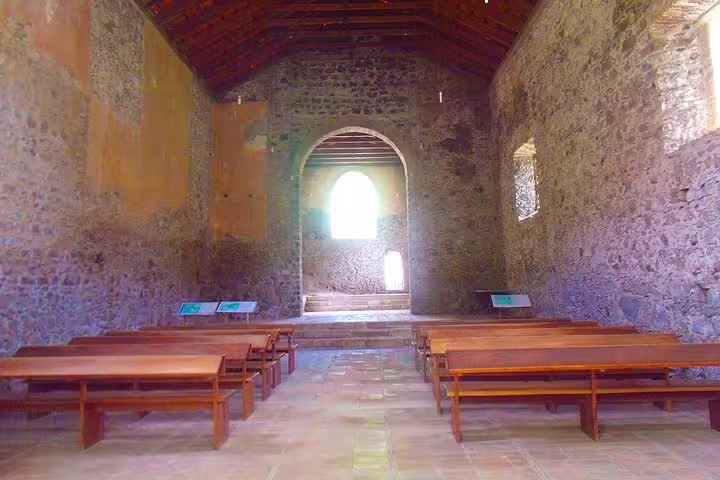 Interior of historic stone chapel with wooden benches in Mindelo, São Vicente Island tour.