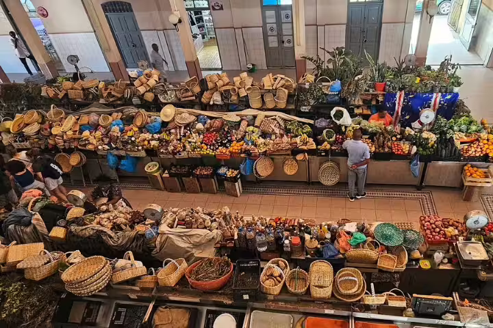 Bustling Mindelo market with colorful fruits, vegetables, and baskets, offering a vibrant experience on the City Walking Tour.