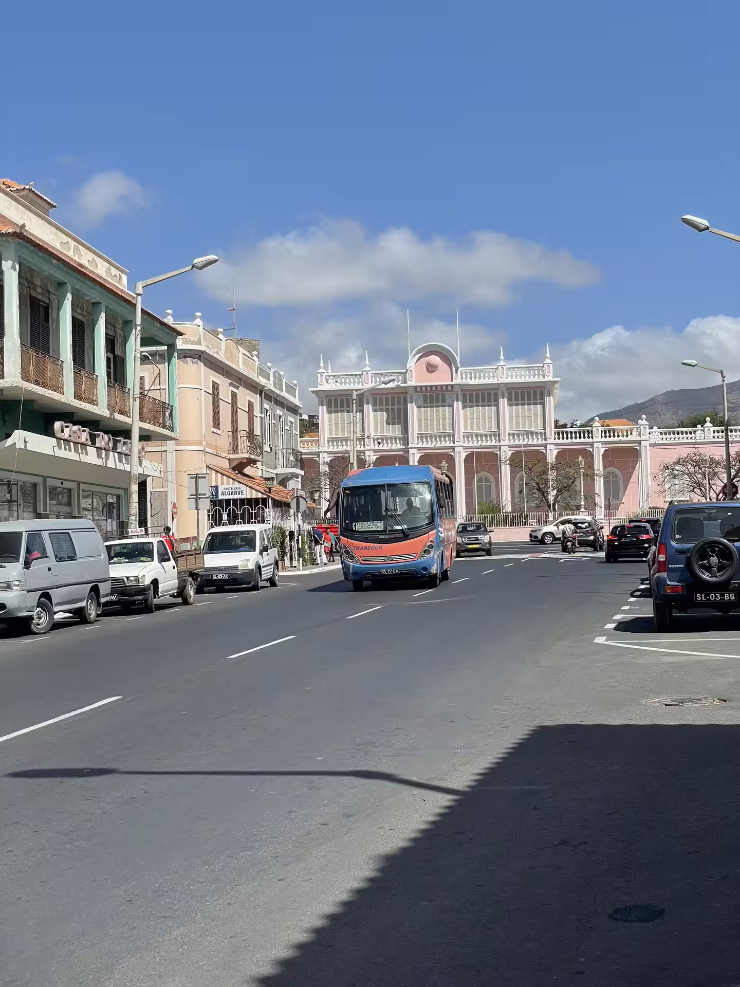 Street view of vibrant Mindelo, São Vicente, showcasing colorful colonial architecture and bustling urban life on a sunny day.