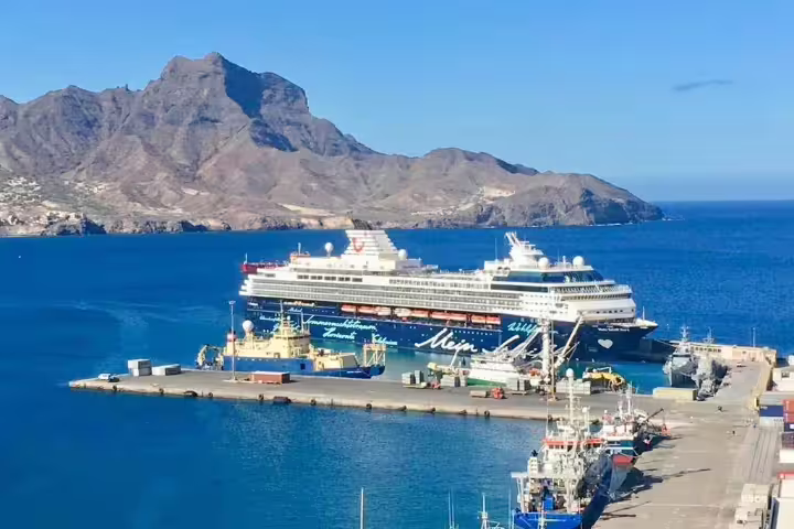 Cruise ship docked at Mindelo port in São Vicente with stunning mountainous backdrop on a sunny day, ideal for half-day shore excursion.