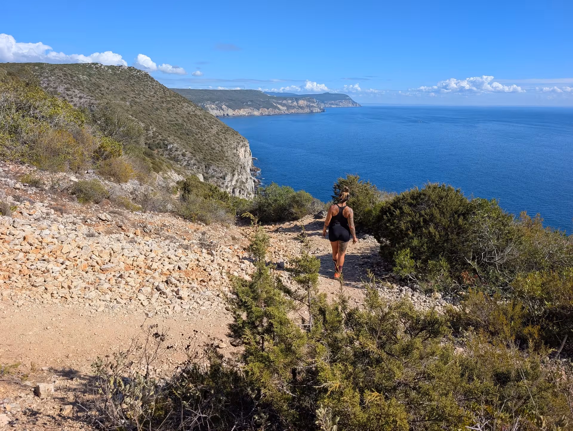 Hiker on rugged cliffside trail with sweeping ocean views, Mindful Coastal Hike guided meditation trek