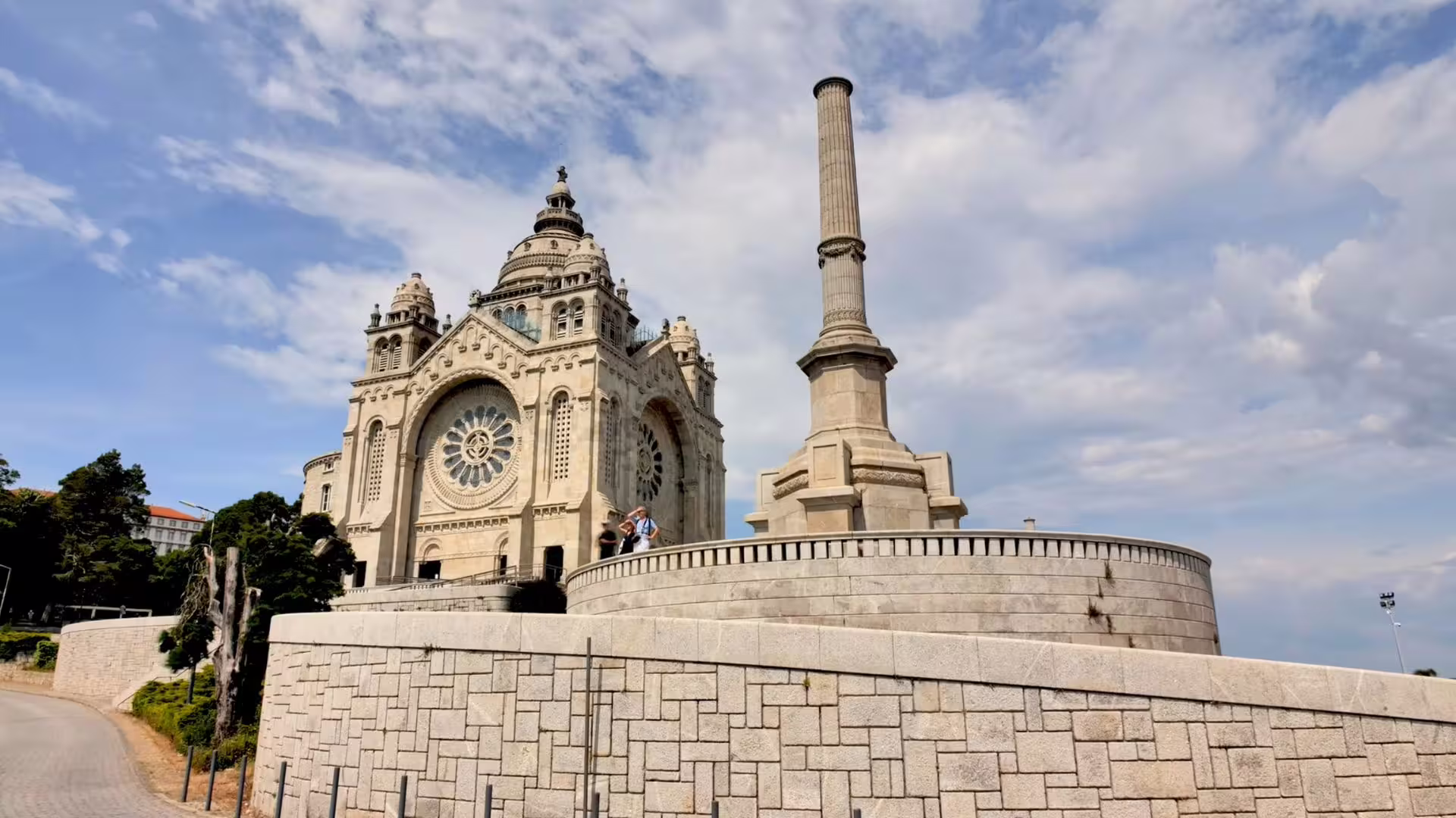 Majestic hilltop basilica with intricate architecture under a cloudy sky in the Minho region, Portugal.