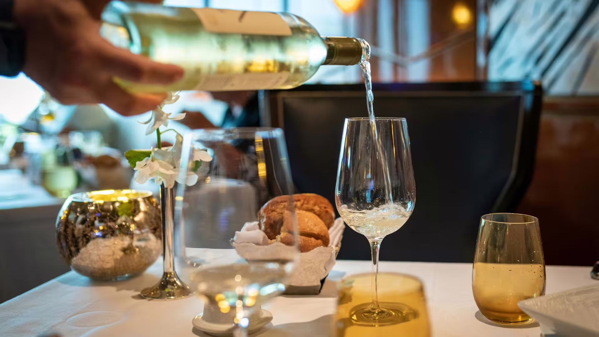 Pouring white wine in elegant restaurant setting, showcasing Minho Region's fine dining experience.