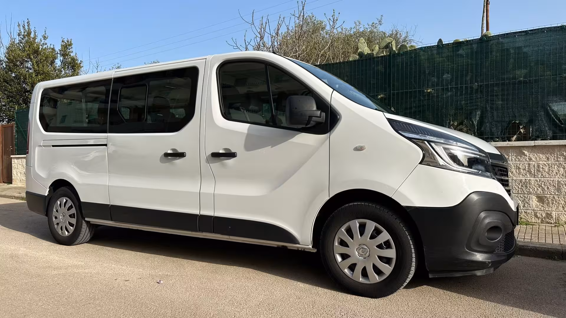 Spacious white minivan ready for tours in Porto Conte Park, Alghero, offering comfortable travel experiences.
