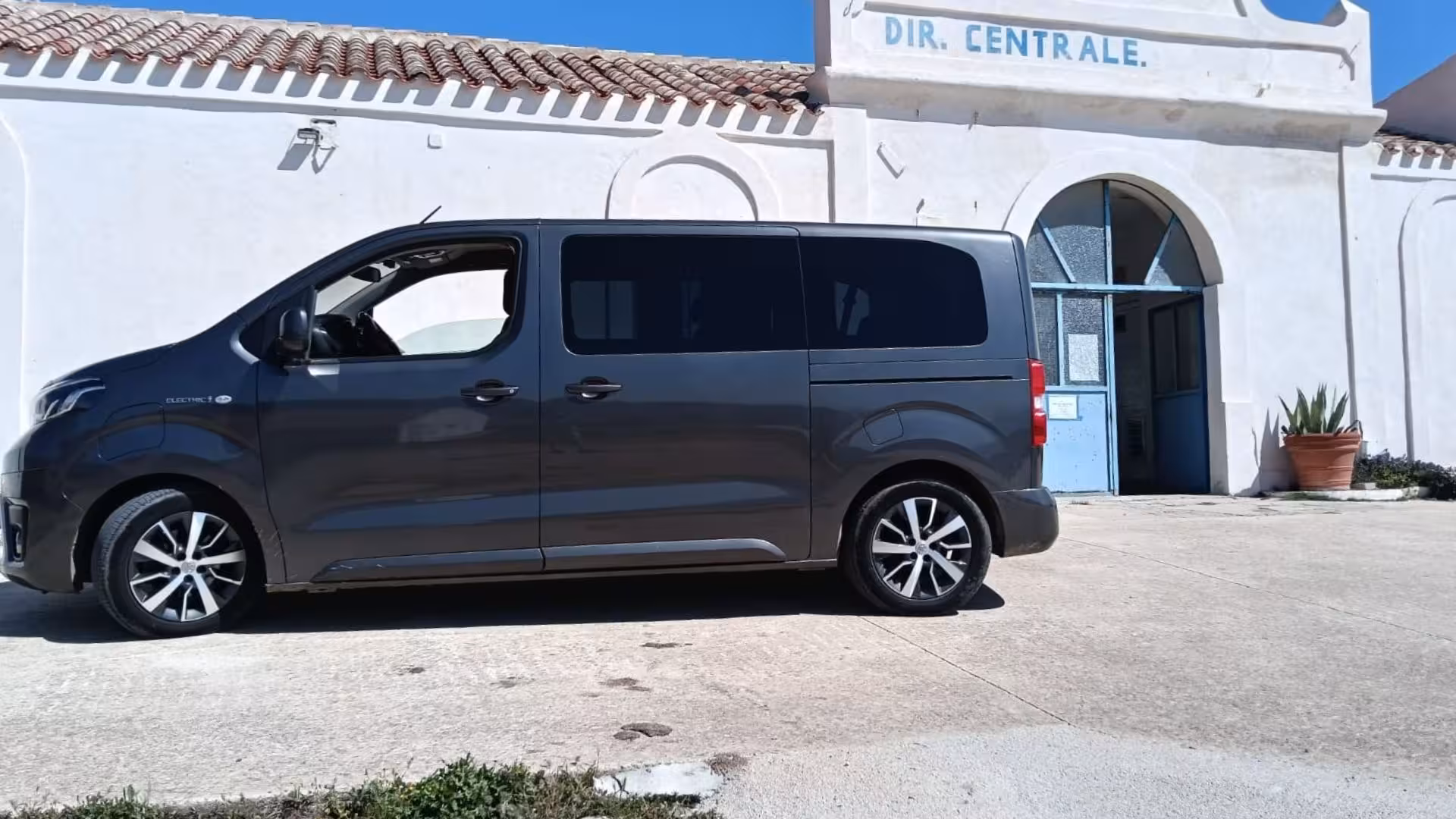 Sleek minivan parked in front of historic white building on Asinara Island, perfect for Porto Torres tour.