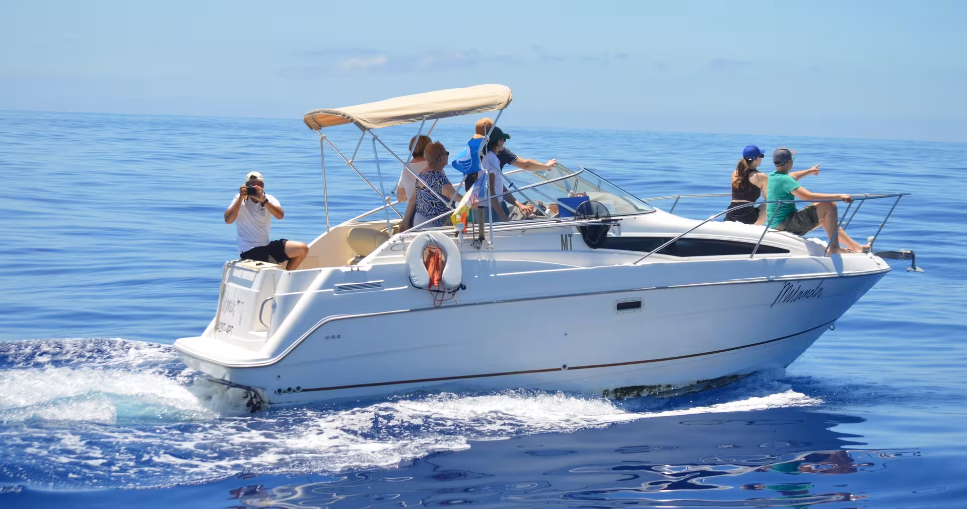 Group enjoys a sunny day on the MIRANDA boat, capturing moments during a private dolphin and whale watching excursion.