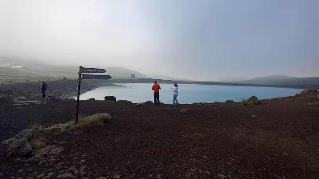 Two people standing beside a large lake in misty weather