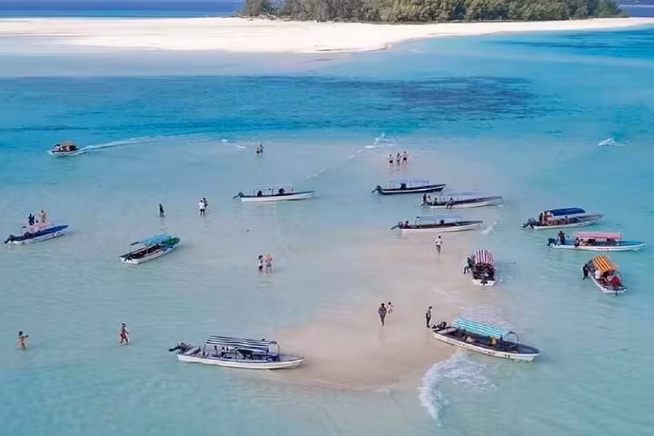 Aerial view of boats anchored on clear turquoise waters near Mnemba Island, perfect for snorkeling and dolphin tours in Zanzibar.