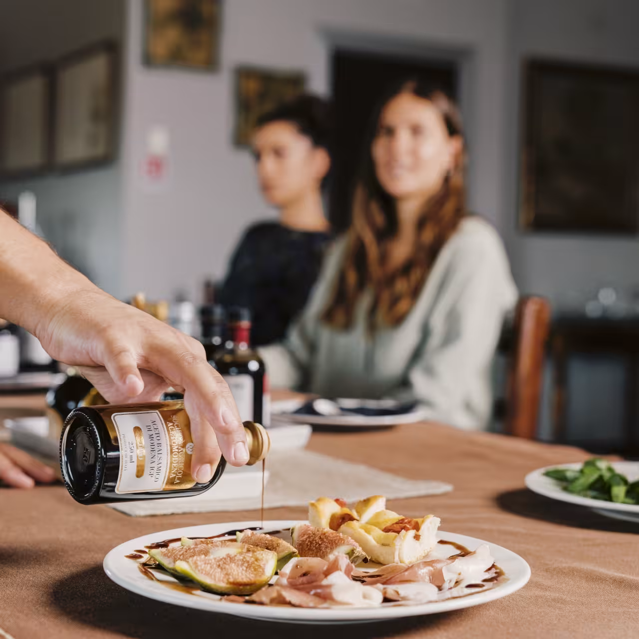 Pouring traditional balsamic vinegar over figs and prosciutto during Modena tasting with Parmigiano and gelato