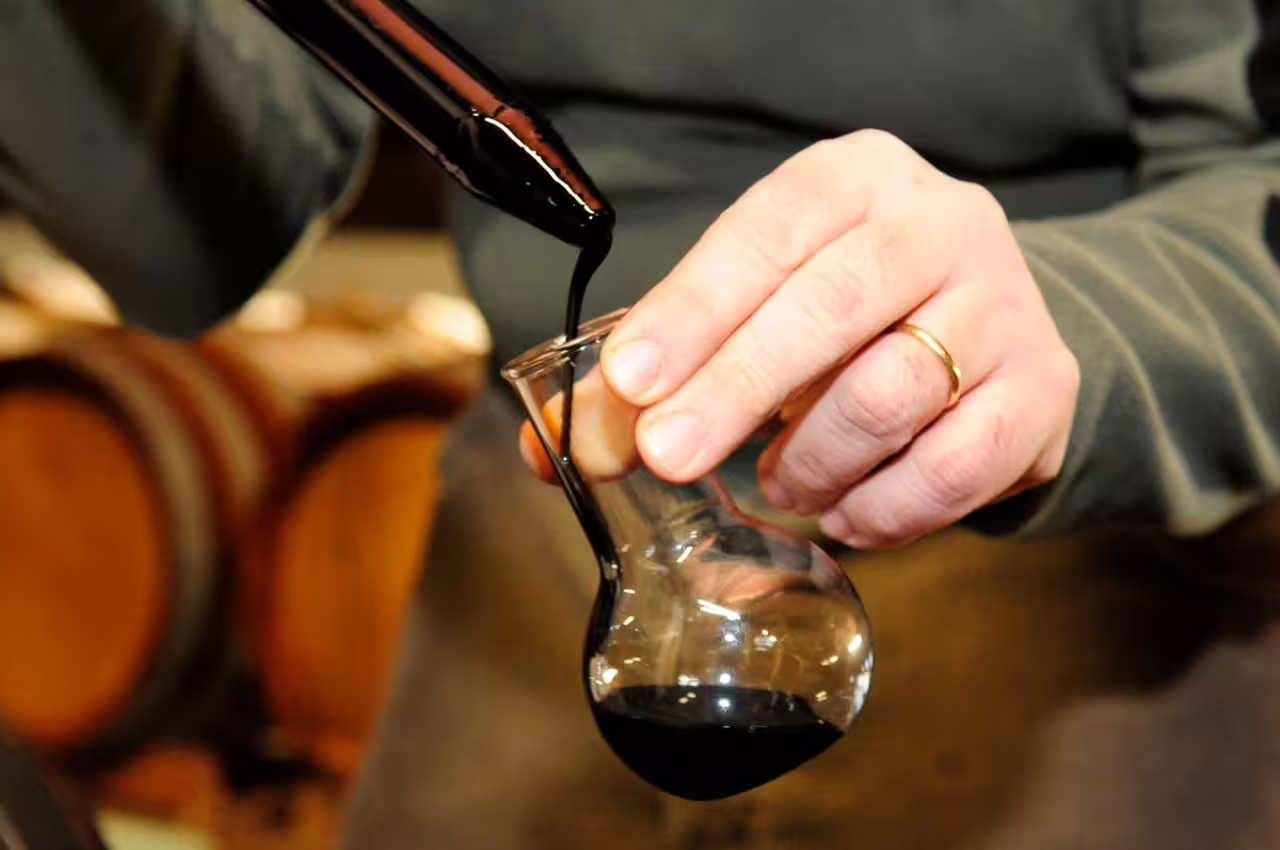 Pouring aged Aceto Balsamico Tradizionale in Modena vinegar cellar during guided tasting experience