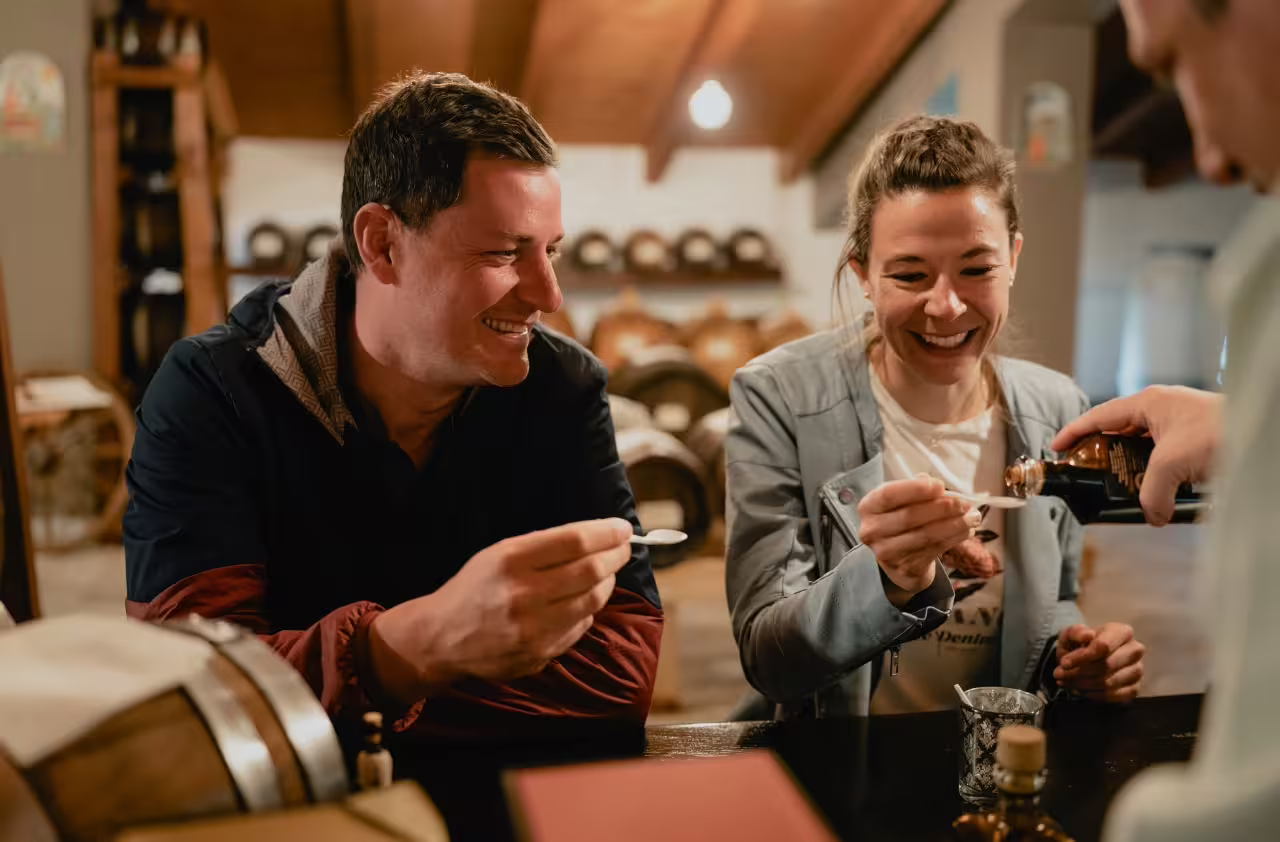 Smiling visitors enjoy tasting premium balsamic vinegar during a guided tour in Modena, showcasing Italian culinary heritage.