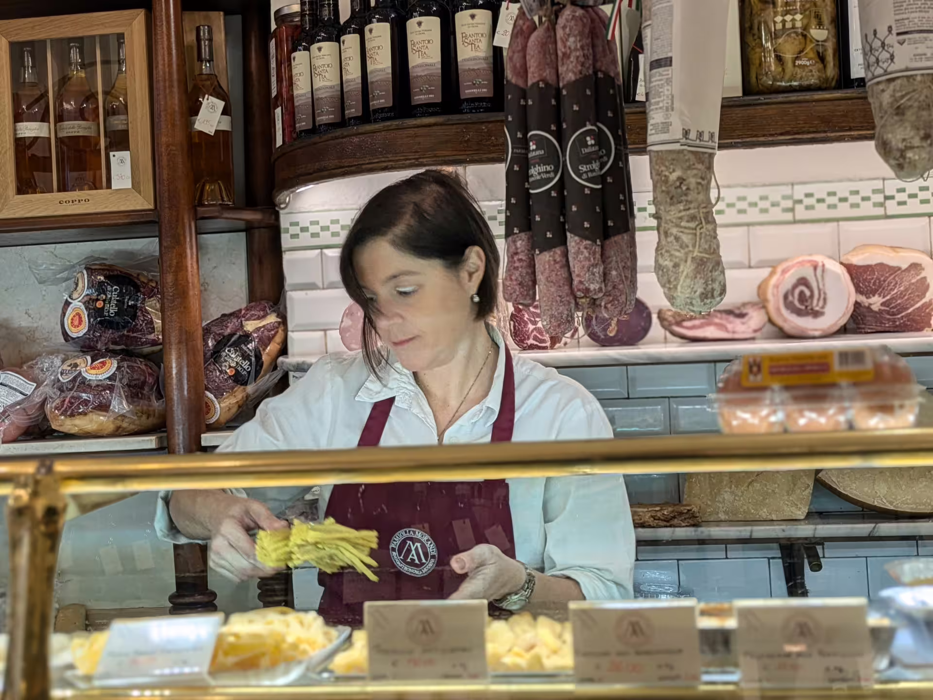 Local vendor serving fresh pasta and cured meats in a traditional Modena delicatessen during a food tour.
