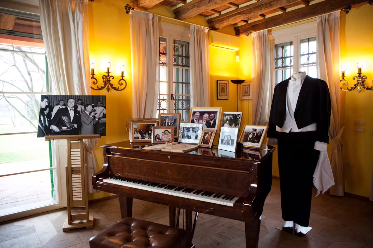 Museo Pavarotti interior in Modena with grand piano, photos and tuxedo display, part of combo museum ticket